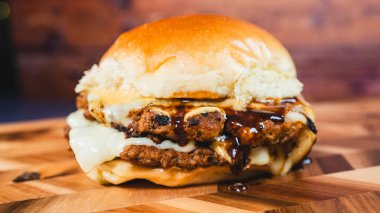 Peynirli leziz sığır burger ve ahşap arka planda kızarmış yumurta.