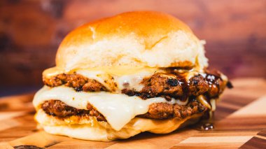 Peynirli burger ve sığır burger. Amerikan hamburgeri sığır eti, sığır eti ve peynirli ve siyah arka planlı ahşap tabakta. Amerikan yemeği. Amerikan hamburgeri.