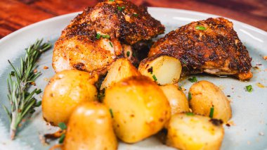 Lezzetli ovalarla kaplanmış kızarmış tavuk budu, fırında altın patates ve taze biberiye ile güzel bir tabak. Sulu, çıtır çıtır ve doyurucu yemekler aile yemekleri ve toplantılar için mükemmel..