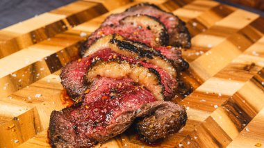 Brisket sliced rare, with a dark, crispy rub from searing, beautifully arranged on a wooden board. Tender pink interior, savory crust, perfect for meat lovers and gourmet presentation.