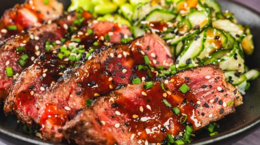 İnce dilimlenmiş sığır filetosu teriyaki, edamame ve sunomono salatası ile güzel bir kase. Yumuşak sığır eti üzerine parlak teriyaki jölesi, taze ve canlı Japon yemeği.