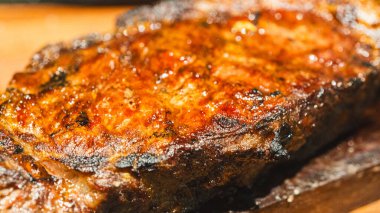 Ender bulunan sulu bir biftek dilimlenmiş ve ahşap bir tahtanın üzerine yerleştirilmiş, içinde pembe bir iç ve karamelize edilmiş kabuk sergileniyor. Yumuşak, lezzetli ve toplantılarda oymak ve hizmet etmek için güzel bir şekilde sunulmuş..