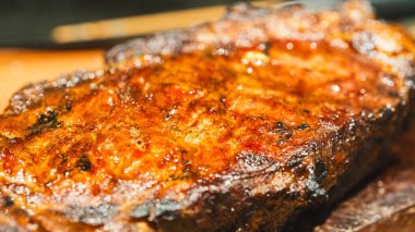 Ender bulunan sulu bir biftek dilimlenmiş ve ahşap bir tahtanın üzerine yerleştirilmiş, içinde pembe bir iç ve karamelize edilmiş kabuk sergileniyor. Yumuşak, lezzetli ve toplantılarda oymak ve hizmet etmek için güzel bir şekilde sunulmuş..