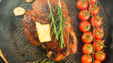 Taze biberiyeyle süslenmiş biftek ve sarmaşıkta doğranmaya hazır vişneli domates. Güzel, kırsal bir sunum, özel günler ve gurme yemekleri için mükemmel..