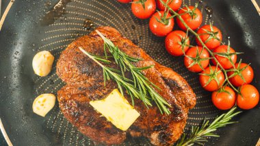 Taze biberiyeyle süslenmiş biftek ve sarmaşıkta doğranmaya hazır vişneli domates. Güzel, kırsal bir sunum, özel günler ve gurme yemekleri için mükemmel..