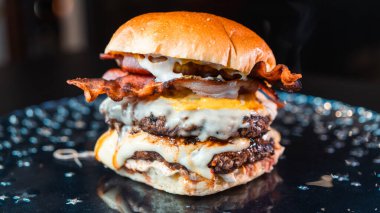 Eritilmiş peynirli, çıtır jambonlu ve keskin hardallı büyük bir çift peynirli hamburger. Sulu, hoşgörülü ve mükemmel istiflenmiş. Bir gurme fast food rüyası gerçek oldu..