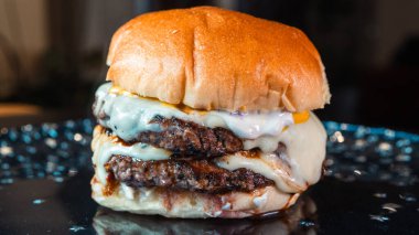 Eritilmiş peynirli, çıtır jambonlu ve keskin hardallı büyük bir çift peynirli hamburger. Sulu, hoşgörülü ve mükemmel istiflenmiş. Bir gurme fast food rüyası gerçek oldu..