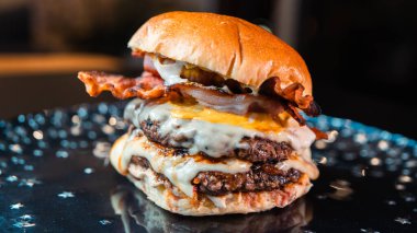 Eritilmiş peynirli, çıtır jambonlu ve keskin hardallı büyük bir çift peynirli hamburger. Sulu, hoşgörülü ve mükemmel istiflenmiş. Bir gurme fast food rüyası gerçek oldu..