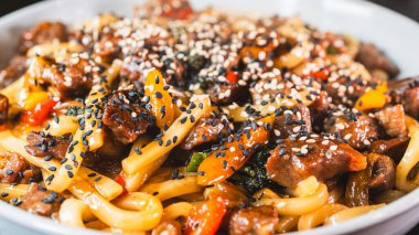 Susam tohumlu, taze sebzeli, dumanı üstünde güzel bir biftek udon kasesi. Zengin et suyu, taze sığır eti ve canlı renkler. Japon yemek severler için mükemmel..