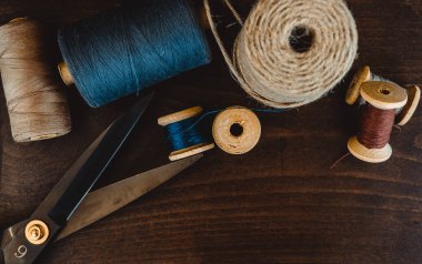 Retro dikiş aletleri: eski makas, gri kumaş üzerindeki iplik bobinleri. Terzinin masası. Tekstil veya ince kumaş üretimi.