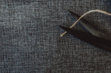 Retro dikiş aletleri: eski makas, gri kumaş üzerindeki iplik bobinleri. Terzinin masası. Tekstil veya ince kumaş üretimi.