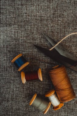 Retro dikiş aletleri: eski makas, gri kumaş üzerindeki iplik bobinleri. Terzinin masası. Tekstil veya ince kumaş üretimi.