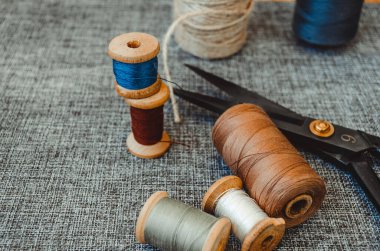 Retro dikiş aletleri: eski makas, gri kumaş üzerindeki iplik bobinleri. Terzinin masası. Tekstil veya ince kumaş üretimi.