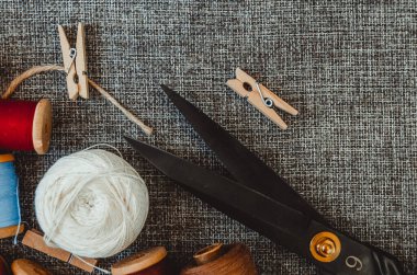 Retro dikiş aletleri: eski makas, gri kumaş üzerindeki iplik bobinleri. Terzinin masası. Tekstil veya ince kumaş üretimi.