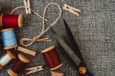 Retro dikiş aletleri: eski makas, gri kumaş üzerindeki iplik bobinleri. Terzinin masası. Tekstil veya ince kumaş üretimi.