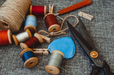 Retro dikiş aletleri: eski makas, gri kumaş üzerindeki iplik bobinleri. Terzinin masası. Tekstil veya ince kumaş üretimi.