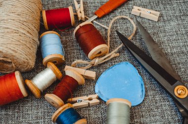 Retro dikiş aletleri: eski makas, gri kumaş üzerindeki iplik bobinleri. Terzinin masası. Tekstil veya ince kumaş üretimi.