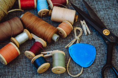 Retro dikiş aletleri: eski makas, gri kumaş üzerindeki iplik bobinleri. Terzinin masası. Tekstil veya ince kumaş üretimi.