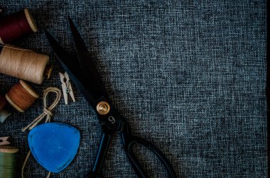 Retro dikiş aletleri: eski makas, gri kumaş üzerindeki iplik bobinleri. Terzinin masası. Tekstil veya ince kumaş üretimi.