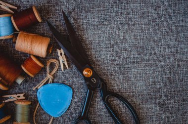 Retro dikiş aletleri: eski makas, gri kumaş üzerindeki iplik bobinleri. Terzinin masası. Tekstil veya ince kumaş üretimi.