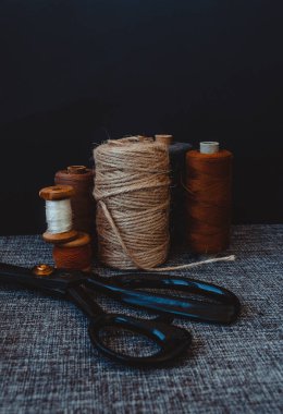 Retro dikiş aletleri: eski makas, gri kumaş üzerindeki iplik bobinleri. Terzinin masası. Tekstil veya ince kumaş üretimi.