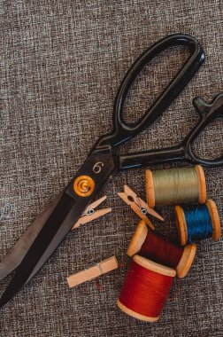 Retro dikiş aletleri: eski makas, gri kumaş üzerindeki iplik bobinleri. Terzinin masası. Tekstil veya ince kumaş üretimi.