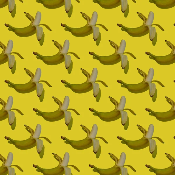 Juicy ripe banana pattern on a yellow background from above with shadow. Seamless background with bananas. Tropical abstract background.