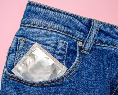 Genç erkeklerin ön cebi, güvenli seks konsepti, parmakları olan şehvetli bir adam, kot pantolonundan prezervatifi çıkarıyor, korunmak için kullanıyor, erkekler prezervatif veriyor.