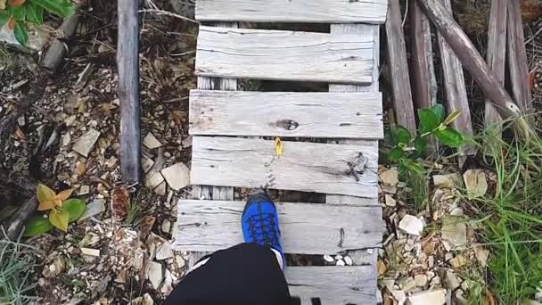古い木製の橋の上を歩く男の足のスローモーションビデオ 自然へのハイキング エコツーリズムの冒険の概念 — ストック動画