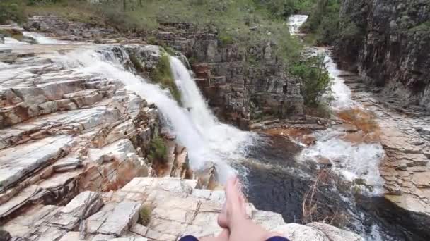 滝の横に座っている男の最初の人のビューは ビューをリラックスして賞賛 エコツーリズムでの冒険の概念 Pov Fpv — ストック動画