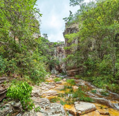 Tortul kayalardan oluşan iki büyük kayalık duvarın arasından geçen nehirden akan su akıntısı. Kayalar yüzünden altın tonları olan su. Capitolio MG, Brezilya 'nın Eko turizm beldesi.