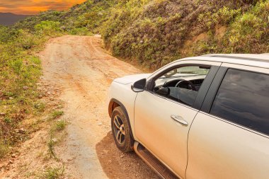 Kayalık bir yolda Sierra 'ya giden SUV arabası gün batımında eğimli zeminde beyaz araba. Çevre turizmi kavramı 4x4 macera. Minas Gerais eyaletinin Brezilya Sierra 'sı.