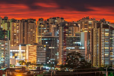 Güçlü bir günbatımında şehrin manzarası ve şehrin ışıkları yanıyor. Londrina şehrindeki Gleba Palhano mahallesinin fotoğrafı, PR, Brazil.