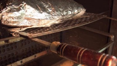 Alüminyum folyoya sarılı büyük bir parça kaburga ızgaranın odun ateşinde yavaşça kızarıyor. Brezilya barbeküsü.