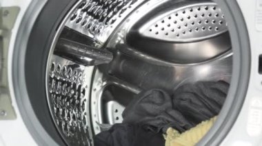 Putting the dirty clothes in the washing machine. Front load washer machine.