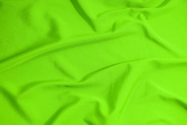 Green fabric with irregular wave shapes, vibrant color. Fabric background in green tone.