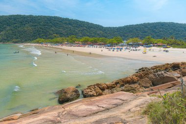 Guaiuba Plajı, Guaruja SP, Brezilya. Sakin denizle küçük körfezin üzerinde güneşli bir gün. Sao Paulo sahilindeki turizm ve boş zamanların görüntüsü. Mata Atlantica bitki örtüsüyle kaplı tepeler manzara.