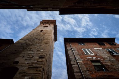 Meşhur Torre delle Ore (saatler kulesi), Lucca (Toskana, İtalya) şehir merkezinde antik ortaçağ taret saati, yakınlardaki dar sokaklardan görülen şehrin simgesi ve simgesi.
