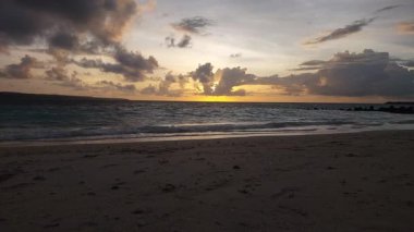 Parlak altın gün batımı okyanus yüzeyine yansıyarak Endonezya, Bali 'deki Kelan plajında sıcak ve huzurlu bir sahil atmosferi yaratıyor..