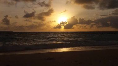Parlak altın gün batımı okyanus yüzeyine yansıyarak Endonezya, Bali 'deki Kelan plajında sıcak ve huzurlu bir sahil atmosferi yaratıyor..