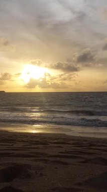 Parlak altın gün batımı okyanus yüzeyine yansıyarak Bali, Kedonganan sahilinde sıcak ve huzurlu bir sahil atmosferi yaratıyor..