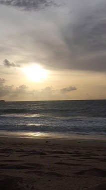 Parlak altın gün batımı okyanus yüzeyine yansıyarak Bali, Kedonganan sahilinde sıcak ve huzurlu bir sahil atmosferi yaratıyor..