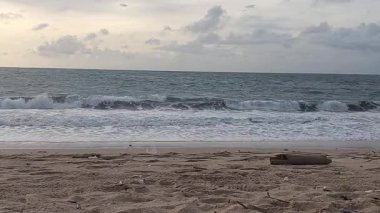 Yumuşak okyanus dalgaları ve bulutlu gökyüzü ile huzurlu kumlu sahil, Kedonganan sahilinde, Bali, Endonezya 'da sakin ve doğal bir kıyı atmosferi yaratıyor..