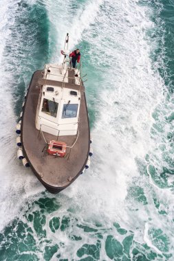 Devriye botu açık denizde yüksek hızda yol alıyor, arkasında güçlü bir uyanış bırakıyor. Üniformalı bir mürettebat güvertede duruyor ve sahil güvenlik görevi, liman idaresi veya pilot tekne faaliyeti gibi profesyonel bir deniz operasyonunu öneriyor..