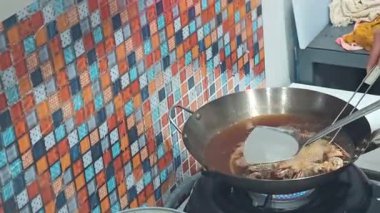 Gaz sobasında kızgın yağla dolu karbon çelik bir tavada birkaç parça uskumru balığı kızartma işlemini gösteren bir video. Bir metal süzgeç ve spatula, yağdan kıtır, altın-kahverengi balığı kaldırmak için kullanılır..