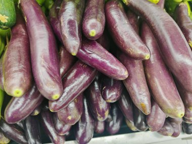 Bir markette ya da çiftçi pazarında üst üste dizilmiş pek çok uzun, olgun mor patlıcanın (brinjal) tepeden aşağı görüntüsü.