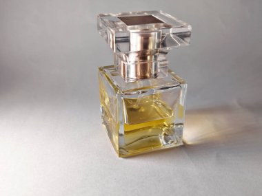 Kehribar sıvıyla kaplı lüks bir cam parfüm şişesi, yumuşak yansımalarla bembeyaz bir yüzeye yerleştirilmiş. Sıcacık, bulanık arka planı olan minimalist kompozisyon, güzellik ve refah kavramları için mükemmel..