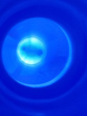 Merkezi, canlı bir mavi ışık kaynağına sahip derin bir lacivert arkaplan içeren dijital illüstrasyon. 