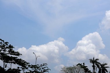 Dağınık beyaz bulutlarla dolu parlak bir gökyüzü. Kompozisyon, kurumsal arkaplanlar, seyahat reklamları veya ilham verici sosyal medya paylaşımları için ideal hale getirerek olumsuz bir alan sunuyor. Profesyonel renk derecelendirme ile yüksek çözünürlük