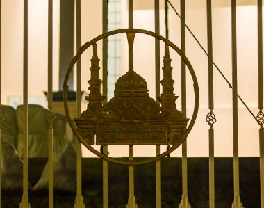 Şehir mimarisinin arka planına karşı hilal ay ve minare tasarımlı bir cami silueti içeren dekoratif metal kapı. İslam kültürü, din, Ramazan ve geleneksel süs tasarımı kavramı.